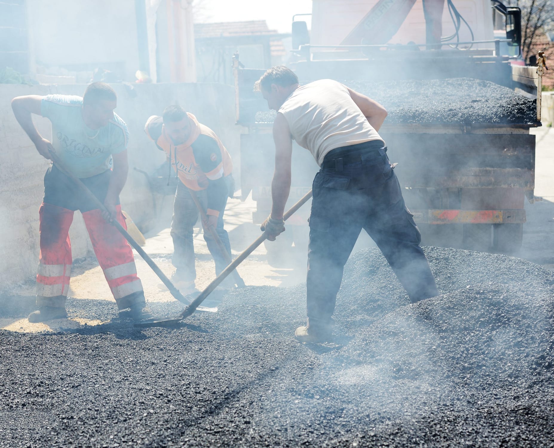 Road construction workers in hot asphalt.